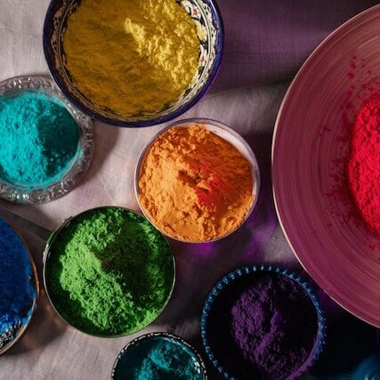 A photo of several bowls of brightly coloured powder.